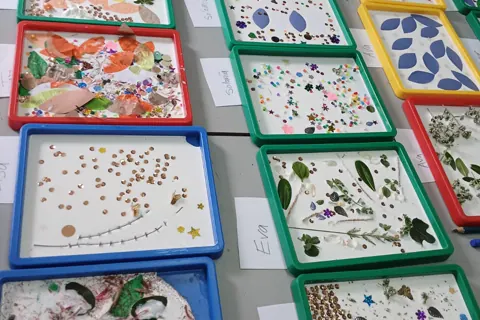 Craft table covered with finished nature collage trays