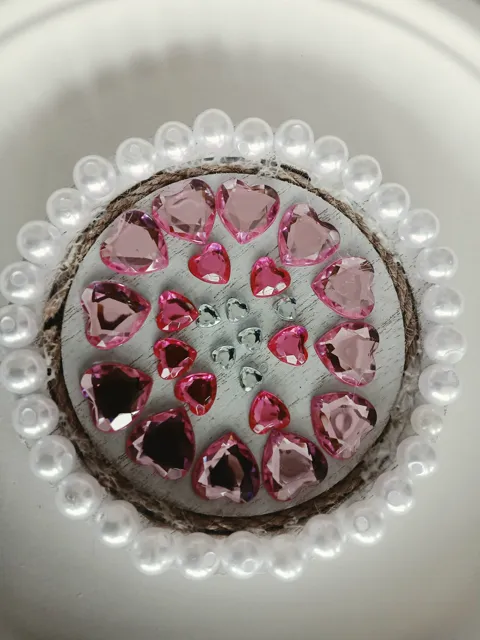 Round artwork decorated with pink heart gems, small clear gems and white pearls