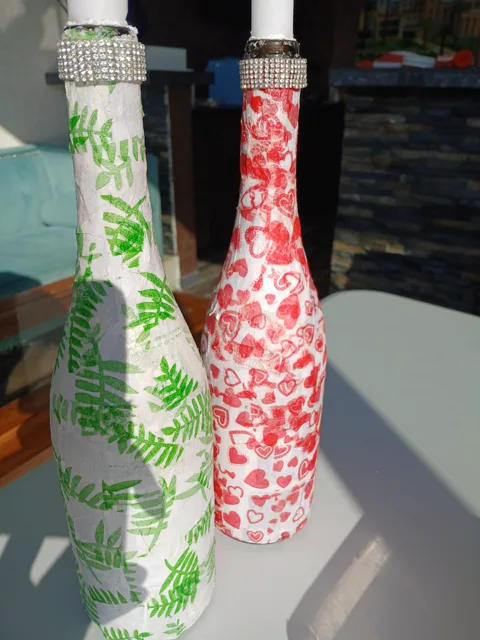 Close view of bead-trimmed candle-holder bottles with fern and floral designs