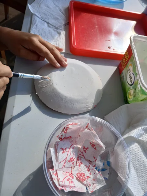 Paper bowl being decorated with patterned tissue paper
