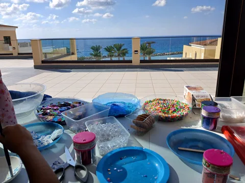 Art materials and colourful crafts on a table beside the sea-view window