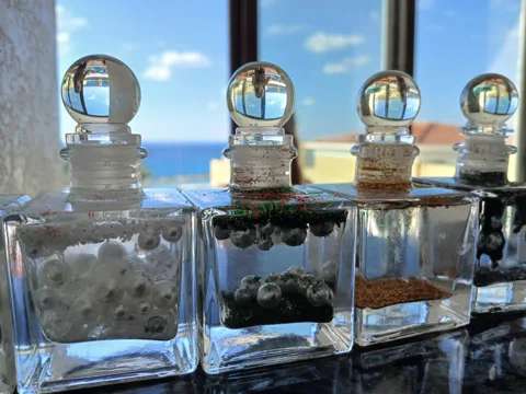 Four glass jars filled with colourful gems and topped with round glass stoppers