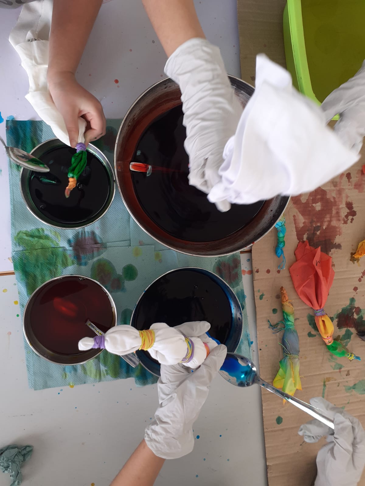 Children dipping tied fabric into dye bowls