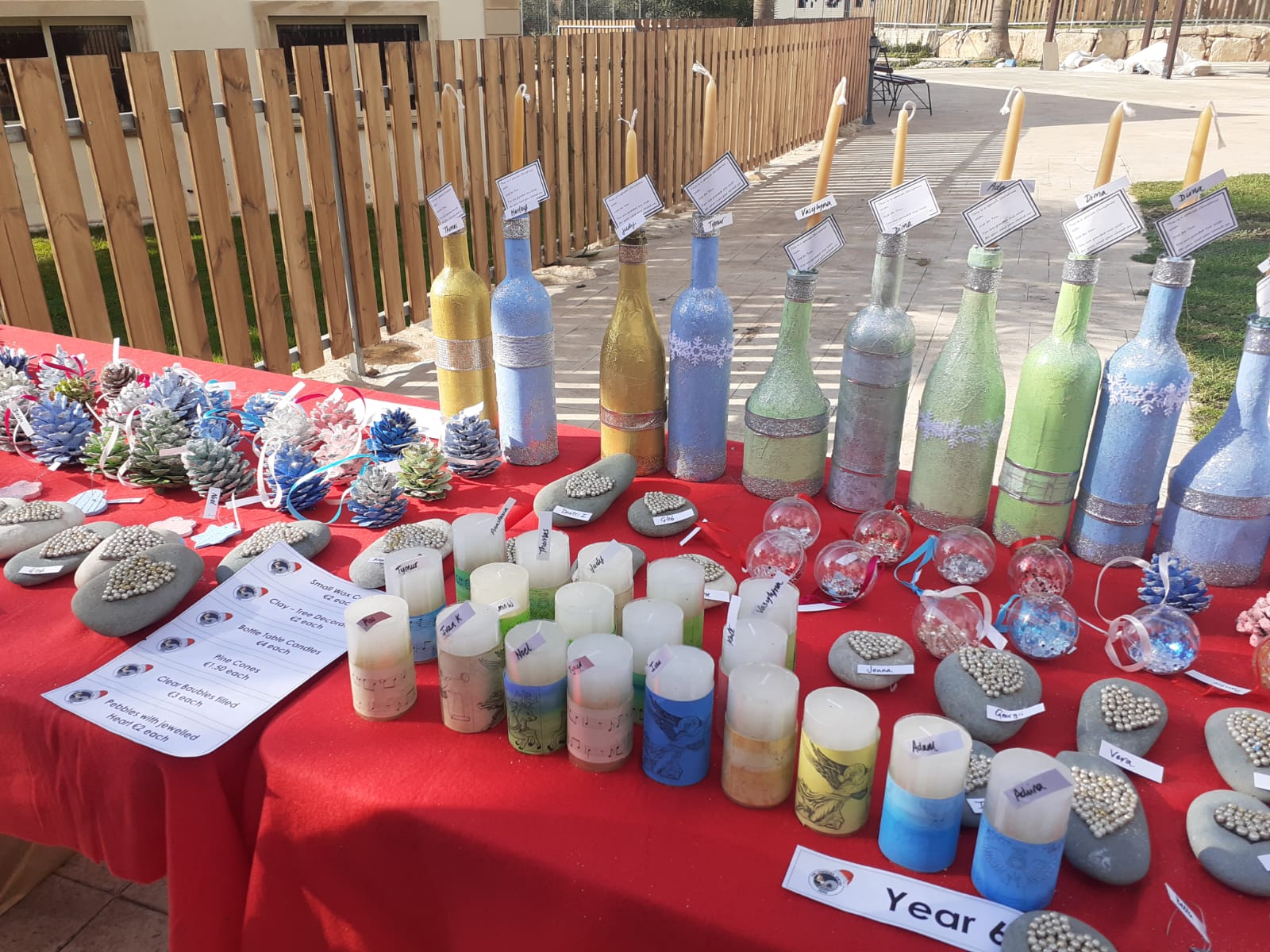 Outdoor craft table with decorated bottles, candles, stones and ornaments