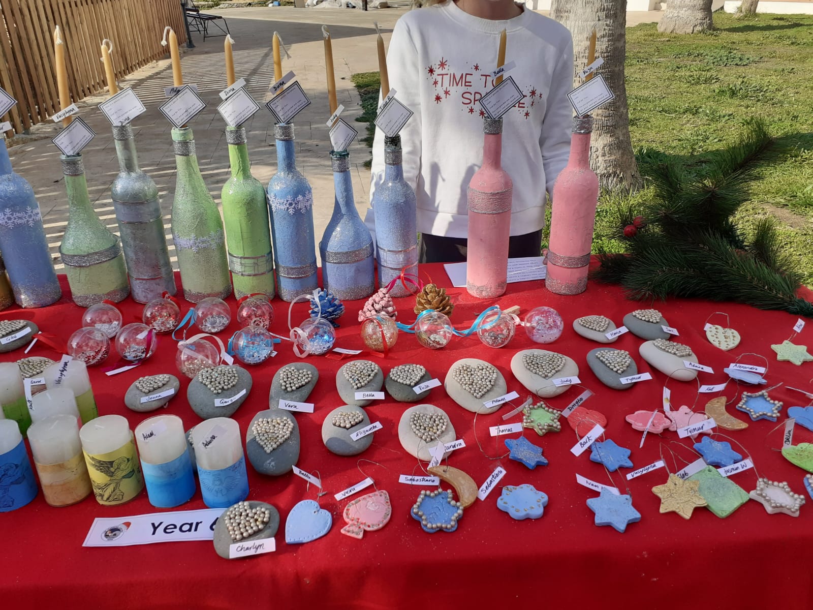 Craft display with painted bottles, decorated pebbles, candles and ornaments