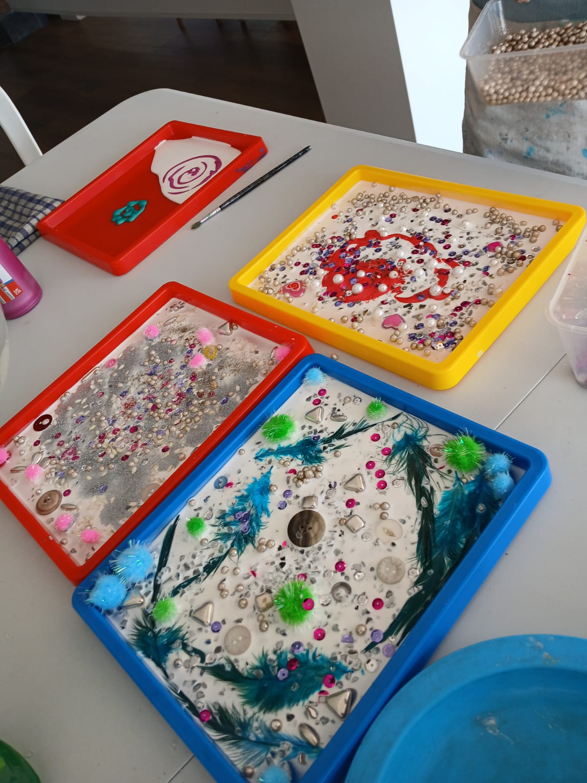 Colourful sensory craft trays with glitter, feathers and gems