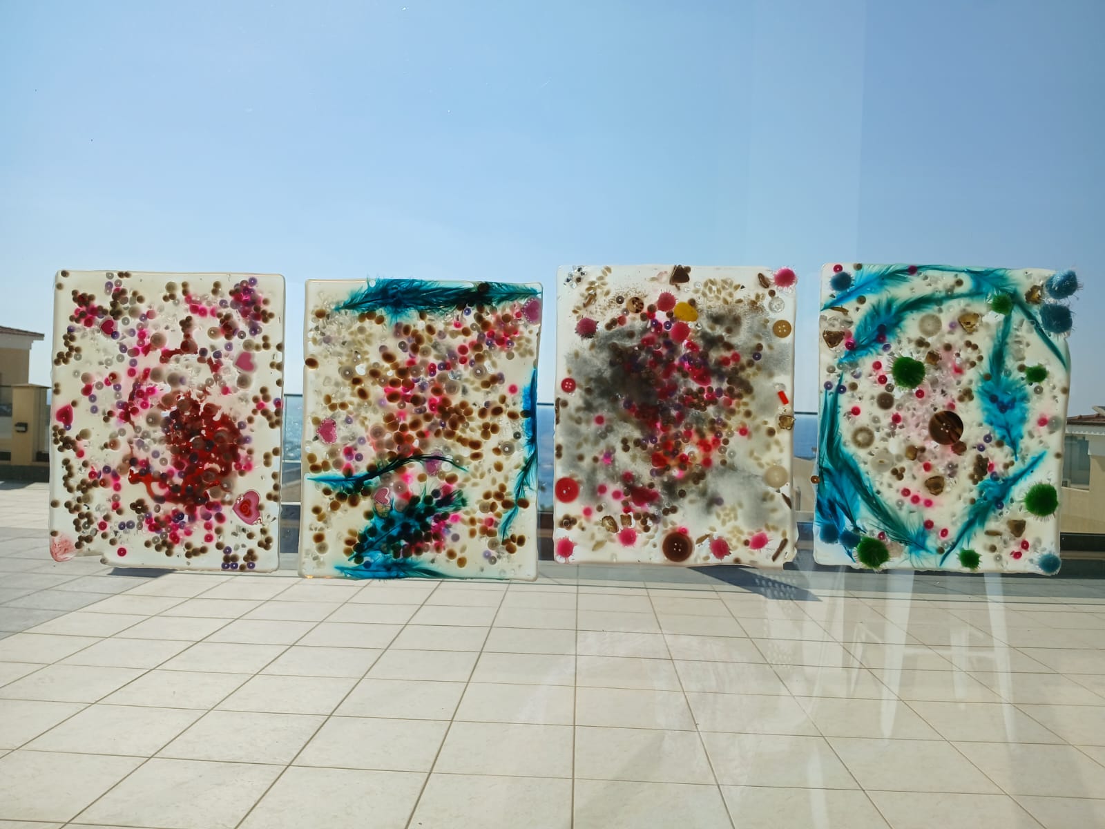 Four translucent sensory artworks displayed against the sea view