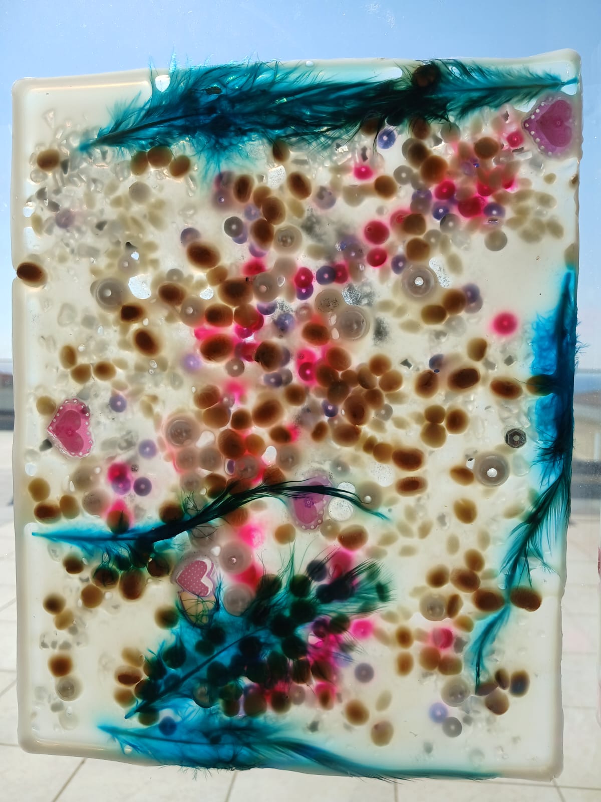 Translucent sensory artwork decorated with blue feathers and heart shapes