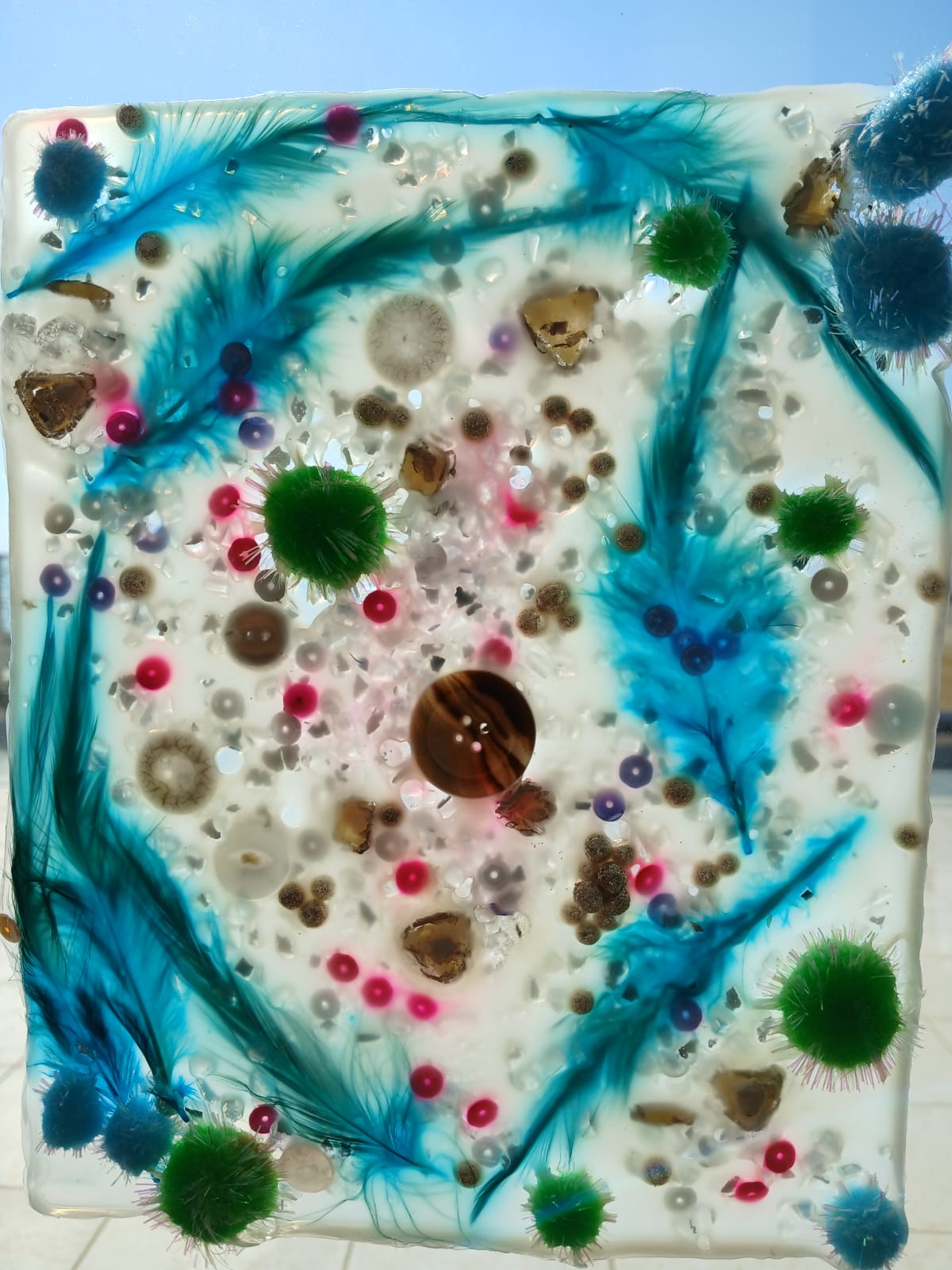 Blue feather sensory panel with beads, buttons and green pom-poms