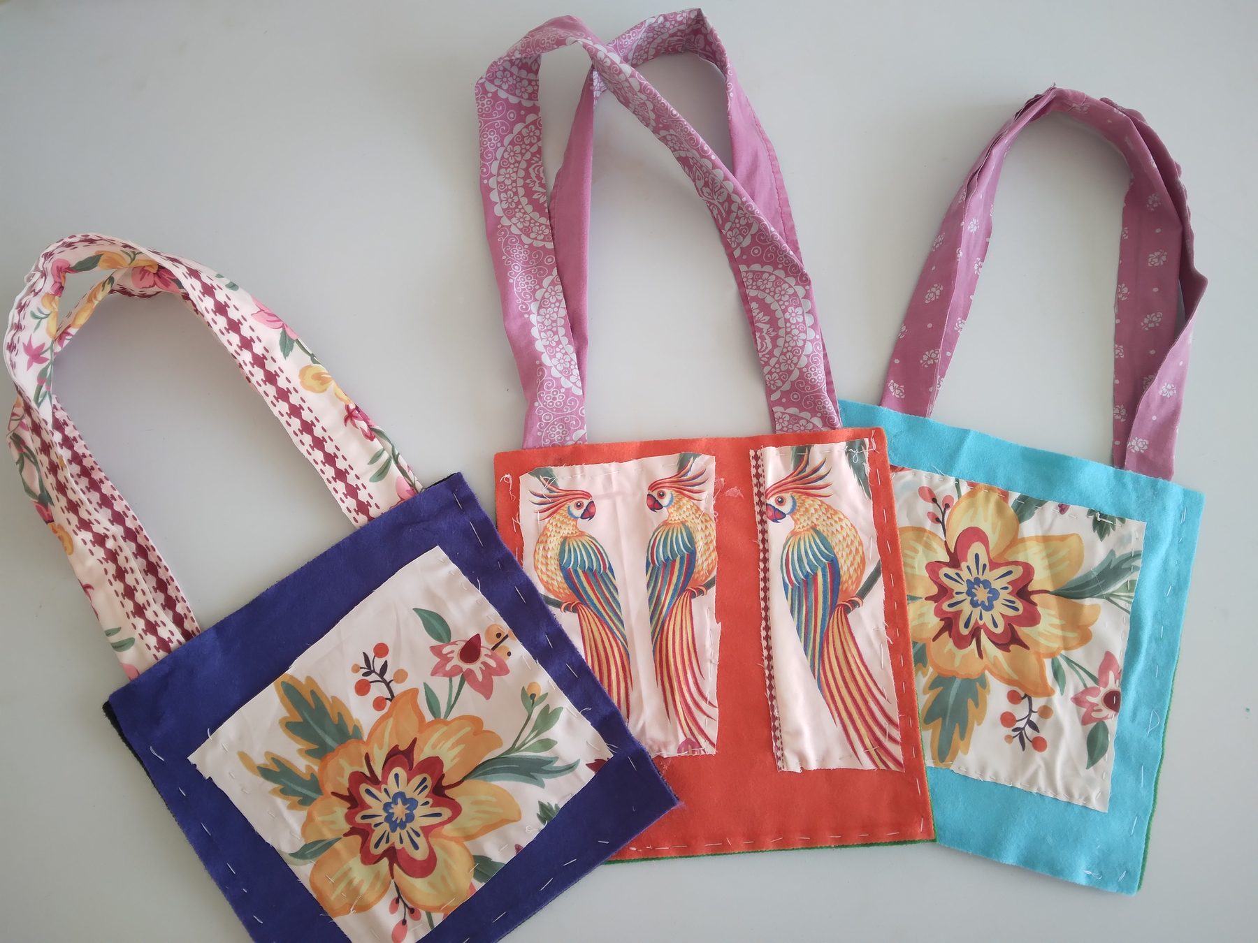 Three handmade fabric bags with floral and parrot panels