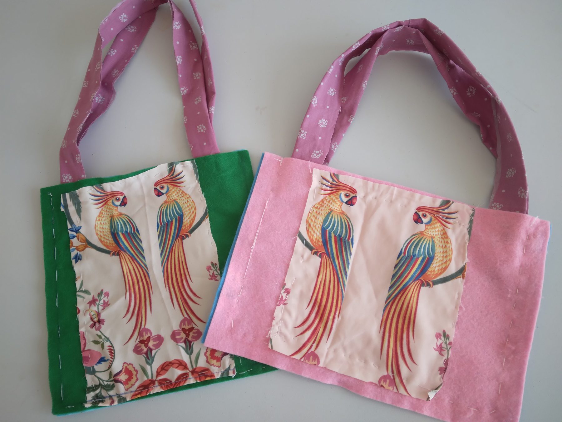 Two handmade fabric bags decorated with colourful parrots