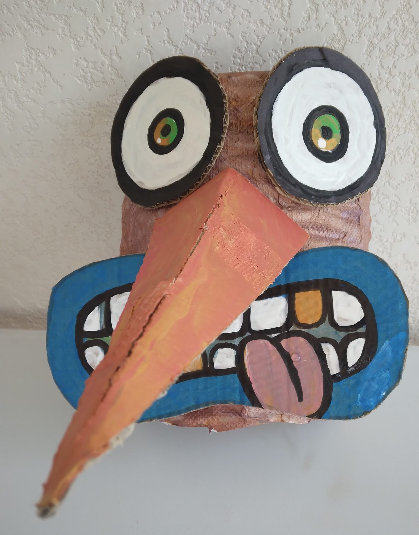 Large painted cardboard character with oversized eyes, nose and teeth